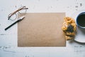 Mockup blank craft sheet of blank craft paper, pen, eye glasses and morning coffee cup with croissant on white wooden Royalty Free Stock Photo