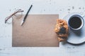 Mockup blank craft sheet of empty paper, pen, eye glasses and morning coffee cup with croissant on white wooden desk Royalty Free Stock Photo