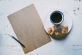 Mockup blank craft sheet of blank craft paper, pen, and morning coffee cup with croissant on white wooden desk Royalty Free Stock Photo