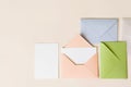 Mockup blank letter inside pink envelope, empty white paper and colorful closed envelopes on beige background, top view. Greeting Royalty Free Stock Photo