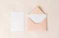 Mockup blank letter inside pink envelope and white paper on beige background, top view. Greeting card concept Royalty Free Stock Photo