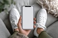 Mockup of a blank smartphone screen held with sneakers in the background Royalty Free Stock Photo