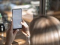 Mockup blonde woman watching her smartphone with empty screen in a cafe Royalty Free Stock Photo