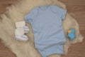 Mockup of blue baby bodysuit on wood background. Blank baby clothes template mock up. Flat lay styled stock photo
