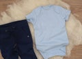 Mockup of blue baby bodysuit on wood background with jeans. Blank baby clothes template mock up. Flat lay styled stock photo