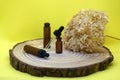 Mockup of brown glass vials with dropper lid on wooden board. Empty glass bottles with pipette, dried hydrangea flower