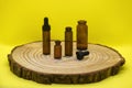 Mockup of brown glass vials with dropper lid on wooden board and on yellow background. Empty glass bottles of different sizes