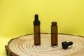 Mockup of brown glass vials with dropper lid on wooden board and on yellow background. Two empty glass bottles and pipette. Royalty Free Stock Photo