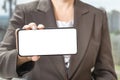 Mockup of a cell phone in horizontal position, a women is holding a phone in the hand on a blurred background