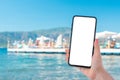 Mockup cell phone image. hand holding white mobile phone with sea and beach blue sky background. roaming on vacation Royalty Free Stock Photo