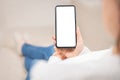 Mockup cellphone. blank white screen smartphone.woman hand holding texting using mobile on sofa at home office.background empty Royalty Free Stock Photo