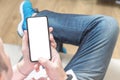 Mockup cellphone. Man sitting on a sofa and holding a blank screen mobile phone