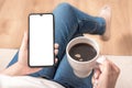 Mockup cellphone. Mockup image of woman`s hands holding mobile phone with blank screen on thigh and coffee cup