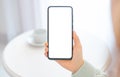 Mockup cellphone. Woman hands using smartphone in sweater. woman sitting at round white table and hold mockup cellphone with white