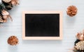 Mockup chalkboard with blank empty screen, new year gift box with Xmas pine tree model, christmas ornaments on white wood desk,