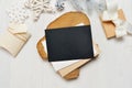 Mockup Christmas black greeting card letter in envelope and gift with white tree, flatlay on a white wooden background Royalty Free Stock Photo