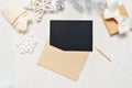 Mockup Christmas black greeting card letter in envelope and pencil, flatlay on a white wooden background, with place for Royalty Free Stock Photo