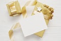 Mockup Christmas greeting card with gold gift ribbon, flatlay on a white wooden background, with place for your text Royalty Free Stock Photo