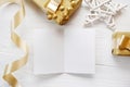 Mockup Christmas greeting card with gold gift ribbon, flatlay on a white wooden background, with place for your text Royalty Free Stock Photo