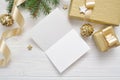 Mockup Christmas greeting card with gold gift ribbon, flatlay on a white wooden background, with place for your text Royalty Free Stock Photo