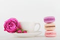 Mockup of coffee cup with rose flower and stack of macaroon on white table with empty space for text and design your blogging. Royalty Free Stock Photo