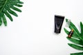 Mockup of cosmetic black cream bottle, Blank label package on a green leaves background.