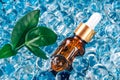 Mockup dropper bottle with natural organic herbal cosmetic oil on blue background of water gel balls. Trendy still life