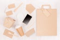 Mockup food takeaway packaging for cafe and restaurant - phone, bag, cardboard box for coffee, noodles on light white wood table.