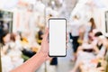 Mockup of hand using mobile phone with copy space blank screen for your advertisement with blurred view of people in public train Royalty Free Stock Photo