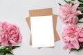 Mockup of horizontal business craft envelope with a sheet of white paper with bouquet of beautiful peonies on a gray background Royalty Free Stock Photo