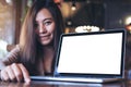 Mockup image of an Asian business woman presenting and showing laptop with blank white screen on wooden table Royalty Free Stock Photo