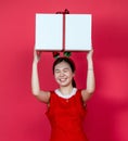 Mockup Image of an Asian Woman Presenting a Big Gift Box With Christmas Attire on a Red Background Royalty Free Stock Photo