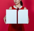 Mockup Image of an Asian Woman Presenting a Big Gift Box With Christmas Attire on a Red Background Royalty Free Stock Photo
