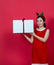 Mockup Image of an Asian Woman Presenting a Big Gift Box With Christmas Attire on a Red Background Royalty Free Stock Photo