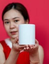 Mockup Image of an Asian Woman Presenting a Blank Mug With Christmas Attire on a Red Background Royalty Free Stock Photo