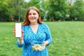 Mockup image of a beautiful woman holding and showing mobile phone with blank screen. Happy woman holding bowl with