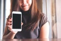 A beautiful woman with smiley face holding and showing white mobile phone with blank black screen in vintage wooden cafe Royalty Free Stock Photo