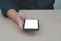 Mockup image blank screen smartphone. Blank white smartphone held by male hand on wooden background.