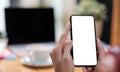 Mockup image blank white screen cell phone.women hand holding texting using mobile on desk at home office Royalty Free Stock Photo