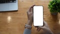 Mockup image blank white screen cell phone.women hand holding texting using mobile on desk at home office Royalty Free Stock Photo