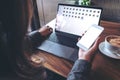 Mockup image of business woman holding mobile phone with blank white screen while using laptop on wooden table Royalty Free Stock Photo