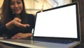 A business woman presenting and showing laptop with blank white screen on wooden table in modern cafe Royalty Free Stock Photo