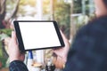 Mockup image of business woman`s hands holding black tablet pc with blank desktop white screen in cafe and green nature Royalty Free Stock Photo