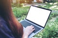 Mockup image of business woman using and typing on laptop with blank white desktop screen , sitting at outdoor with nature Royalty Free Stock Photo