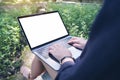 Mockup image of business woman using and typing on laptop with blank white desktop screen , sitting at outdoor with nature Royalty Free Stock Photo