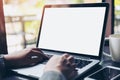 Business woman using and typing on laptop with blank white screen and coffee cup on glass table in modern loft cafe Royalty Free Stock Photo