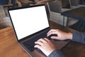 Mockup image of business woman using and typing on laptop with blank white screen and coffee cup on glass table Royalty Free Stock Photo