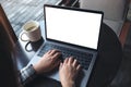 Mockup image of business woman using and typing on laptop with blank white screen and coffee cup on wooden table Royalty Free Stock Photo