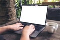 Mockup image of business woman using and typing on laptop with blank white screen and coffee cup on wooden table Royalty Free Stock Photo