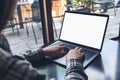 Mockup image of business woman using and typing on laptop with blank white screen on wooden table Royalty Free Stock Photo